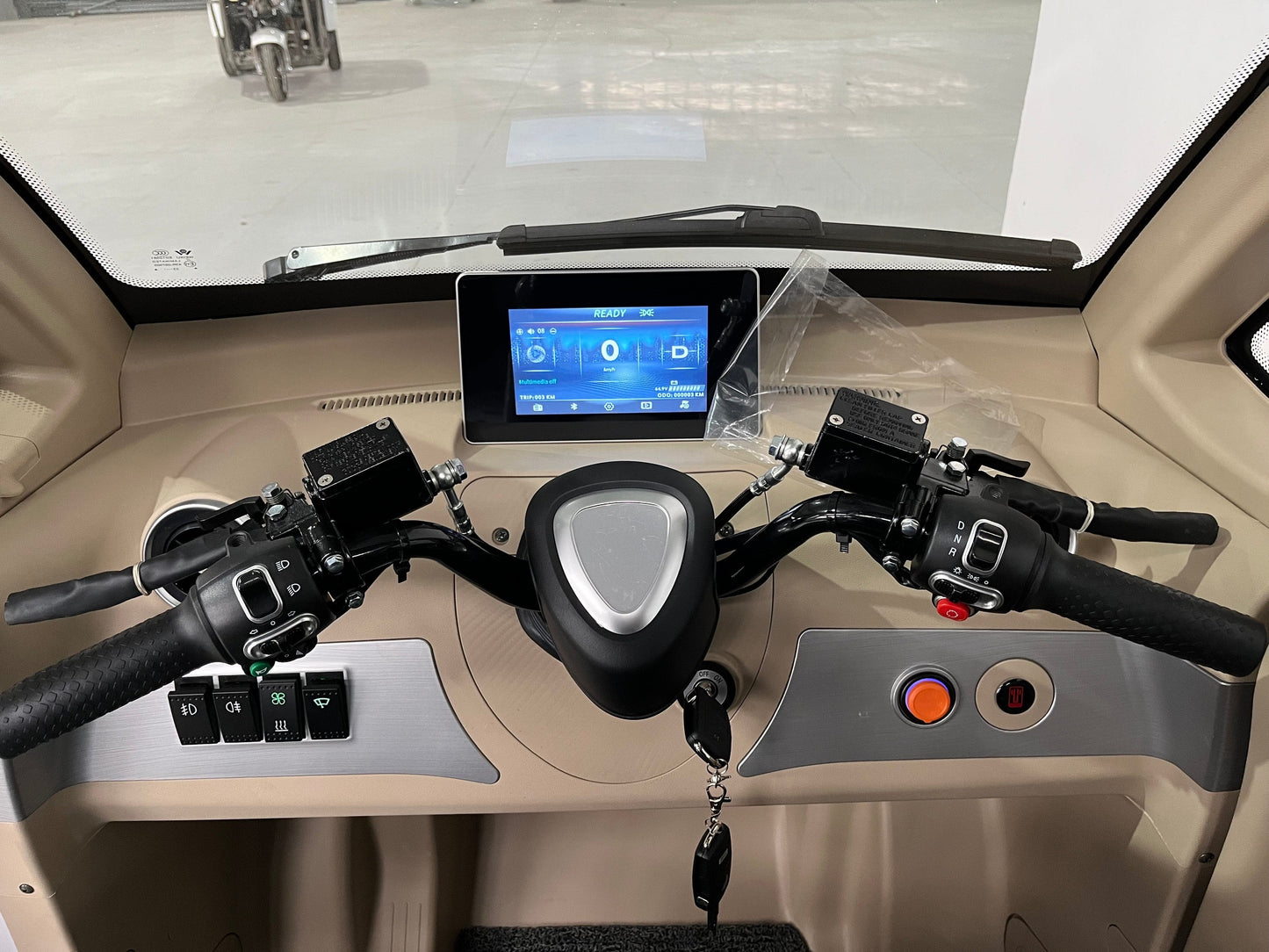 The image displays the control panel and handlebars of a modern enclosed Eclipse EV Nova EV three-wheeled vehicle. It features a digital display in the center, buttons and switches on both handles, and a key hanging from the ignition at the lower center, promising comfortable transportation with its reliable battery.