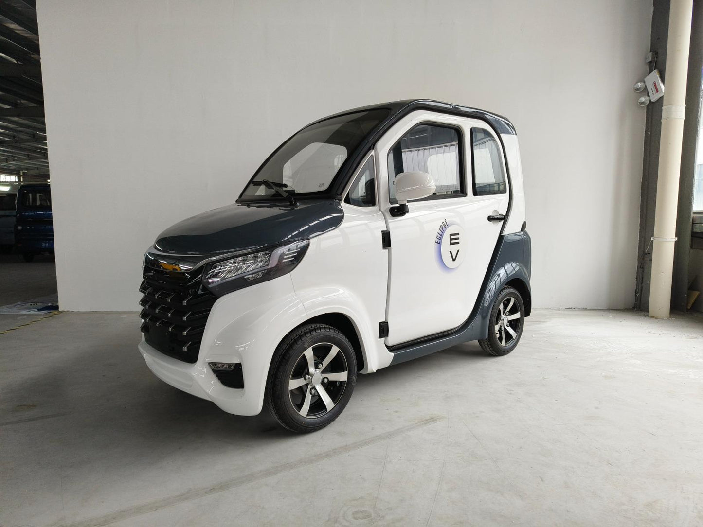 A compact white enclosed scooter with a blue Eclipse EV logo, parked indoors, featuring a modern design with black trims and silver alloy wheels.